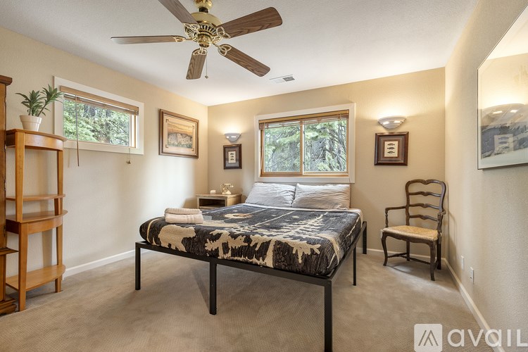 A bedroom with a bed, chair, and ceiling fan.