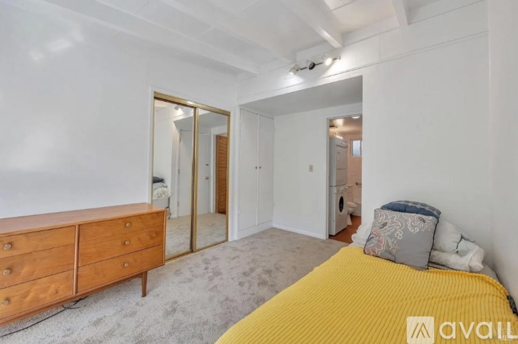 A bedroom with a yellow bed and a wooden dresser with a mirror above it.