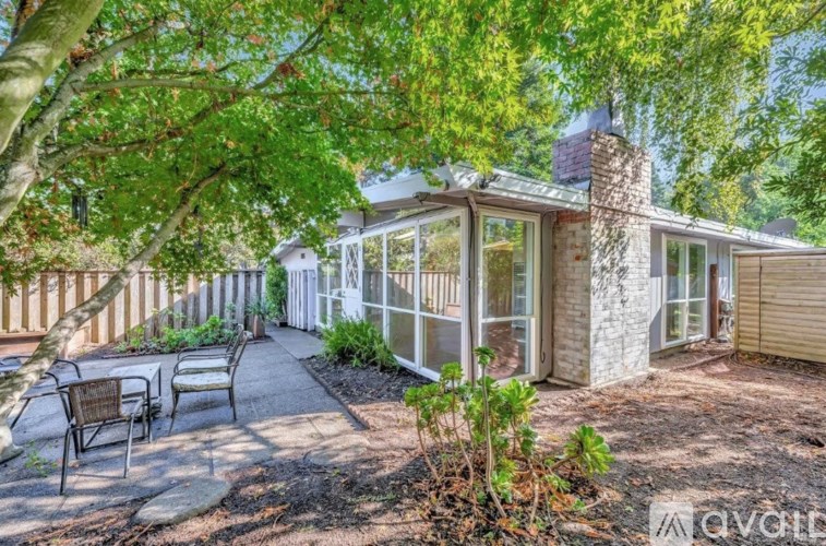 A house with a patio and a tree in front.