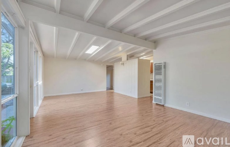 A spacious room with wooden flooring and white walls.