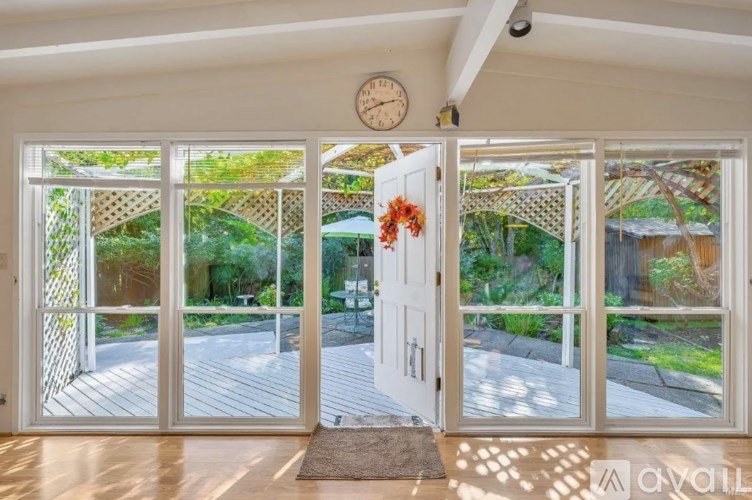 A white door with a clock above it and a rug in front of it.