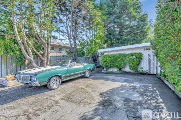 A green vintage car is parked in a driveway.