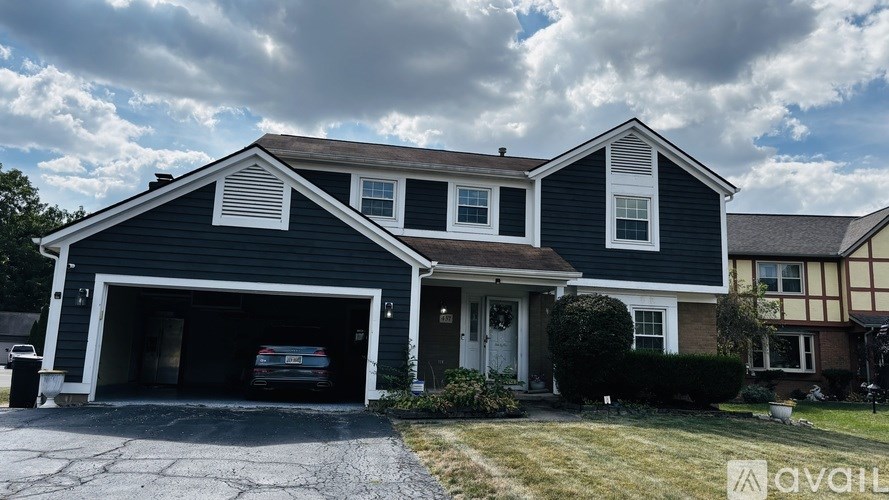 A two-story house with a garage and a car inside.