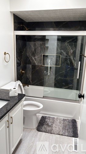 A modern bathroom with a toilet, sink, and glass shower door.