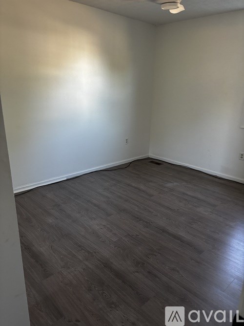 A room with wooden flooring and white walls.