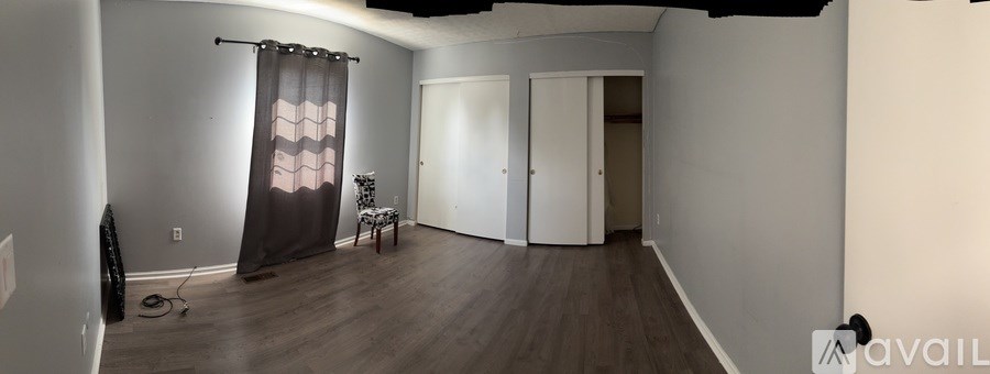 A room with a wooden floor and a window with curtains.