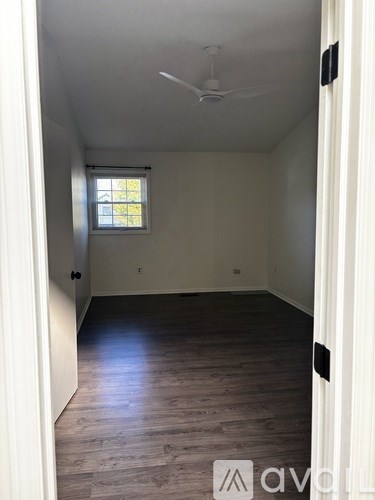 A room with a window and a fan on the ceiling.