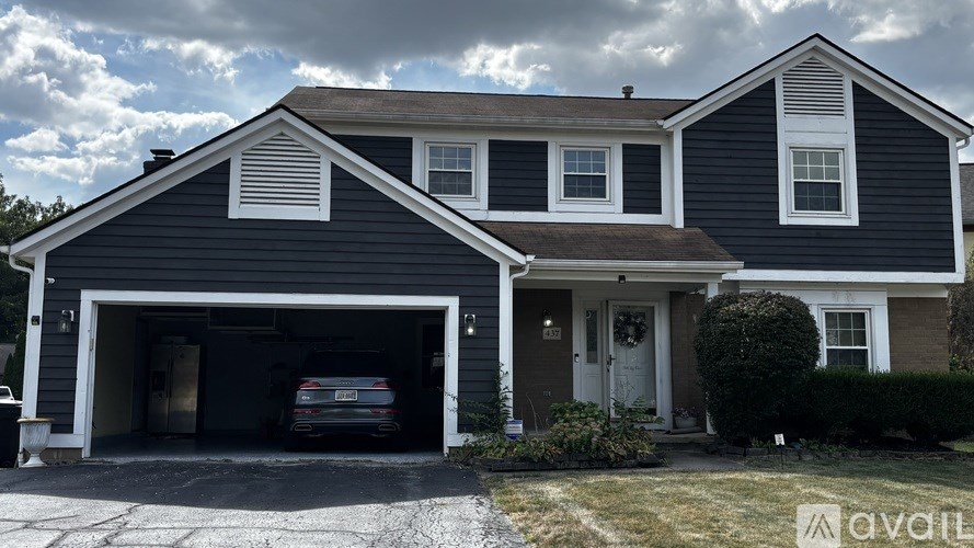 A two-story house with a garage and a car inside.