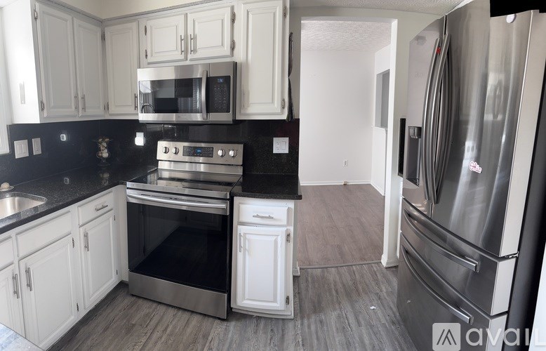 A kitchen with black countertops and stainless steel appliances.