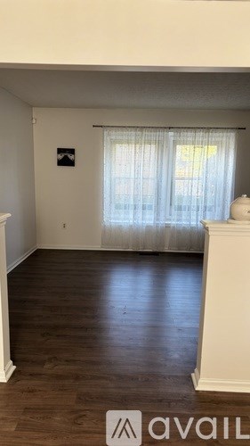 A room with wooden floors and a window with curtains.