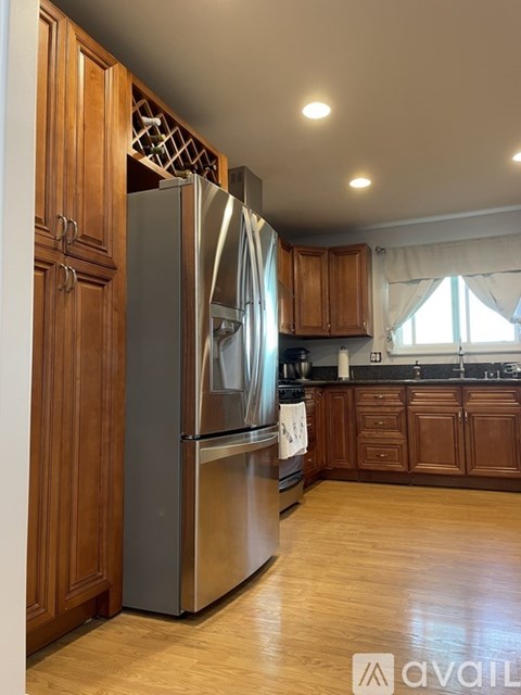 A kitchen with a stainless steel refrigerator and wooden cabinets.