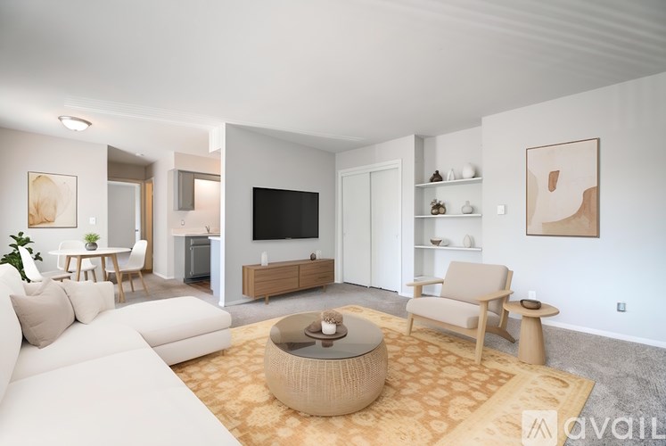 A living room with a white couch, a coffee table, and a television.