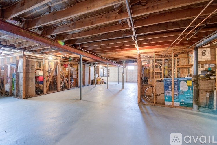 A large, empty room with wooden beams on the ceiling and walls, and a variety of construction materials and tools scattered throughout.
