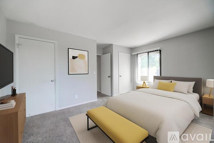 A bedroom with a large bed and a yellow bench.