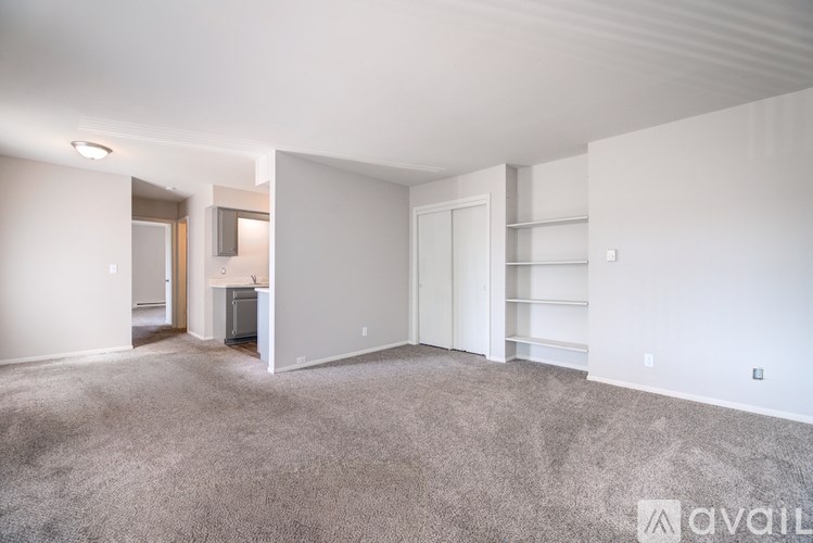 A spacious living room with a carpeted floor and white walls.