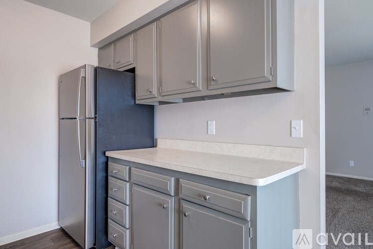 A kitchen with a black refrigerator and grey cabinets.
