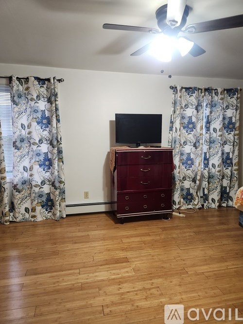 A room with a TV on a cabinet and floral curtains.