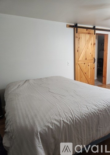 A bed with a white cover is in a room with a sliding door.
