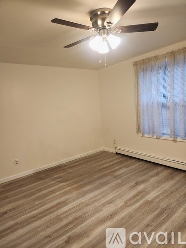 A room with a ceiling fan and wooden flooring.