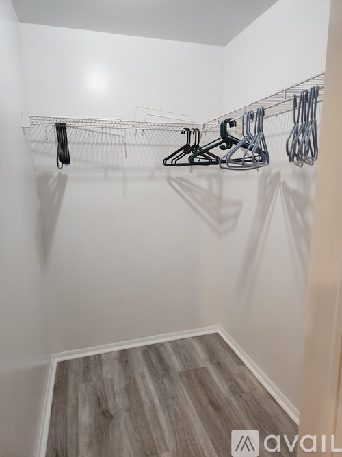 A row of clothes hangers are on a white wall.