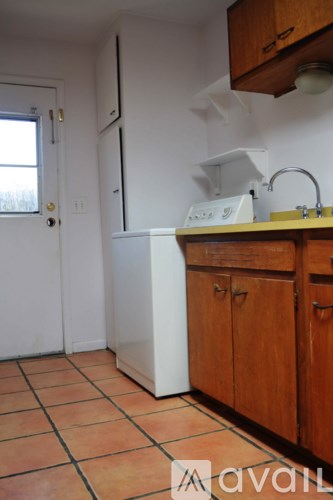 A kitchen with tile flooring and wooden cabinets.