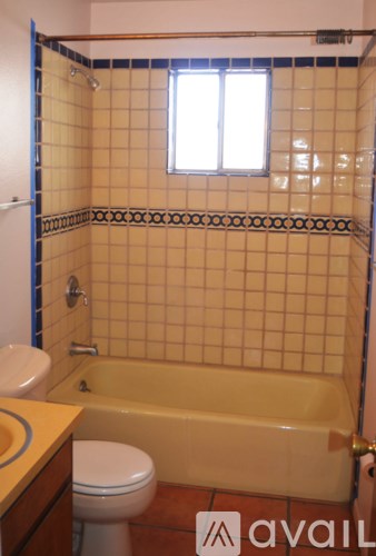 A bathroom with a toilet, tub, and tiled walls.
