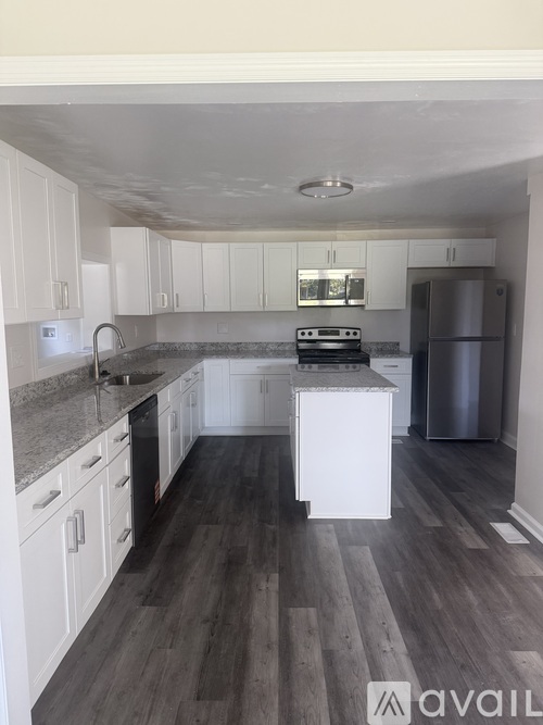A kitchen with white cabinets and a wooden floor.