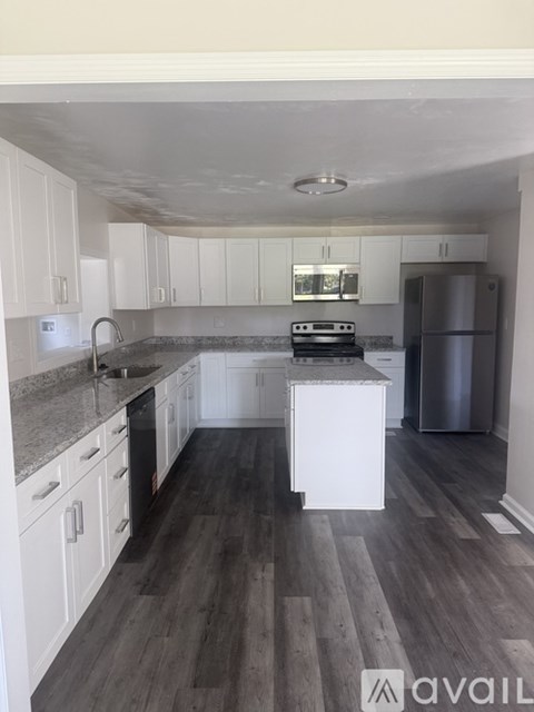 A kitchen with white cabinets and a wooden floor.