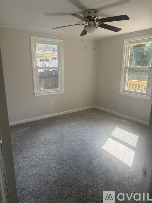 A room with a ceiling fan and two windows.