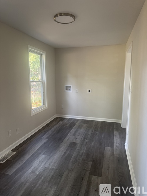 A room with a window and a wooden floor.