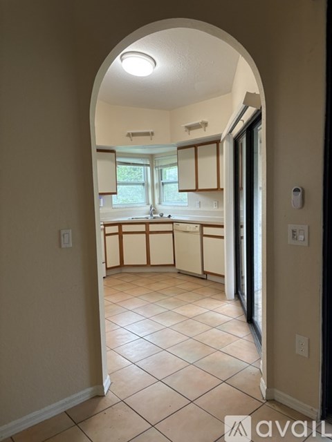 A hallway with a tiled floor and an archway leading to a kitchen.