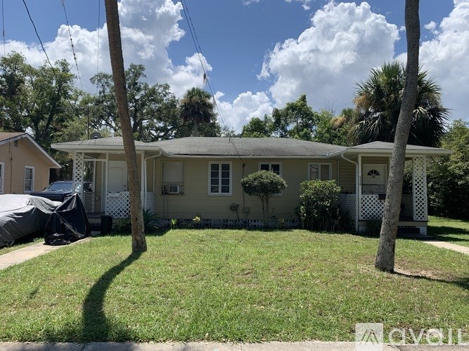 A house with a covered patio and a tree in front.