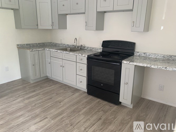 A kitchen with a black oven and white cabinets.