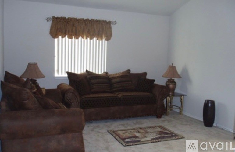 A living room with brown furniture and a window with curtains.
