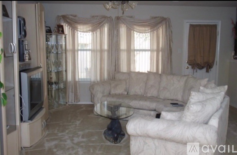 A living room with a white couch and a glass coffee table.