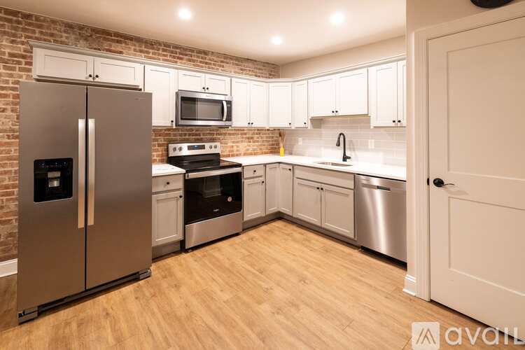 A kitchen with a refrigerator, microwave, oven, and sink.