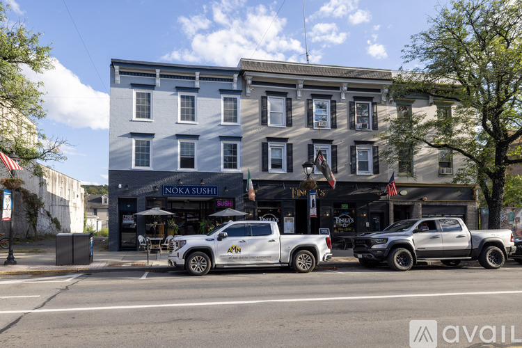 A street view with a building on the left and two trucks parked on the right.