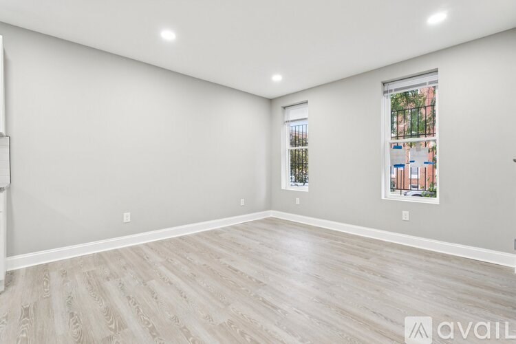A spacious room with wooden flooring and a window showing a view of a building outside.