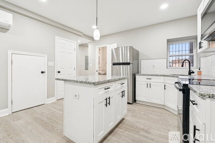 A kitchen with white cabinets and a marble countertop.