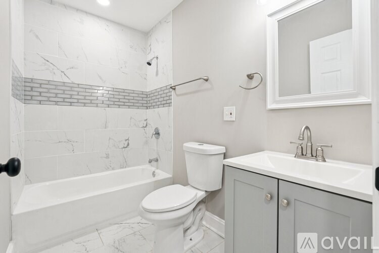 A white bathroom with a marble tile shower.