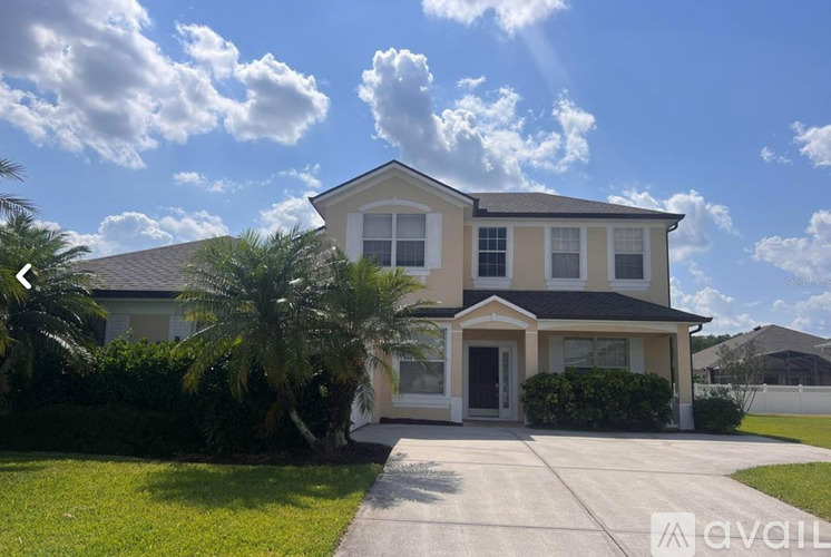 A house with a driveway and palm trees in front.