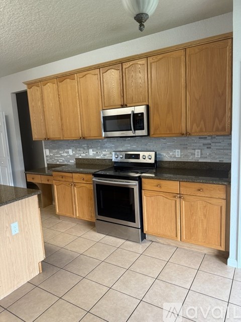 A kitchen with wooden cabinets and a black countertop.