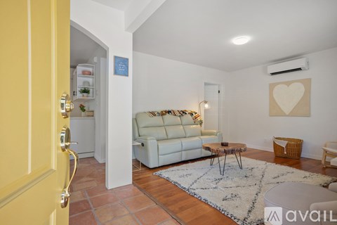 A living room with a white couch and a heart-shaped artwork on the wall.