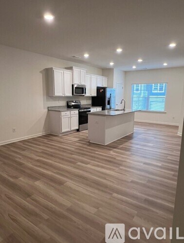 A kitchen with white cabinets and a wooden floor.