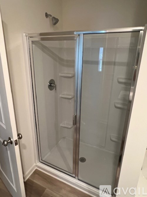 A glass shower door with a handle and a door frame.