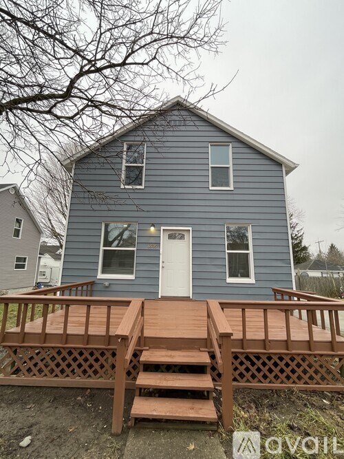 A blue house with a white door and a wooden deck.