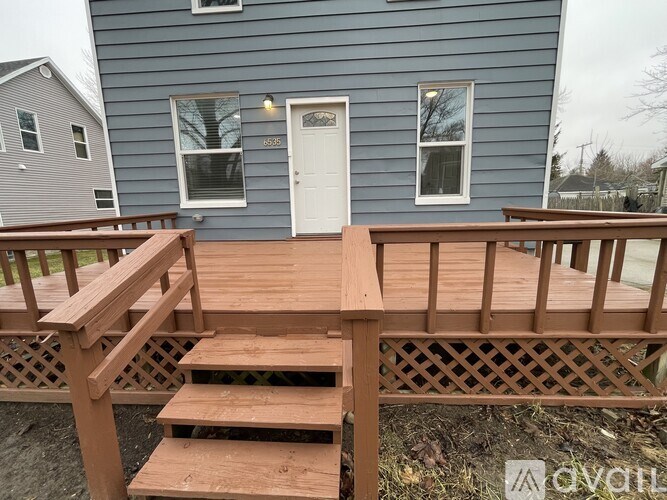 A wooden deck with a lattice design is in front of a blue house.