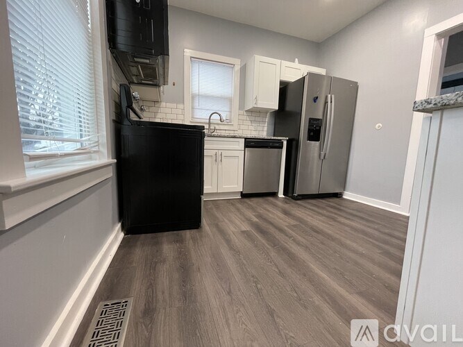 A kitchen with a black fridge and wooden flooring.
