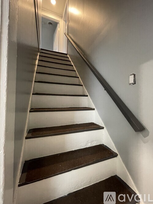 A staircase with a black handrail and white walls.