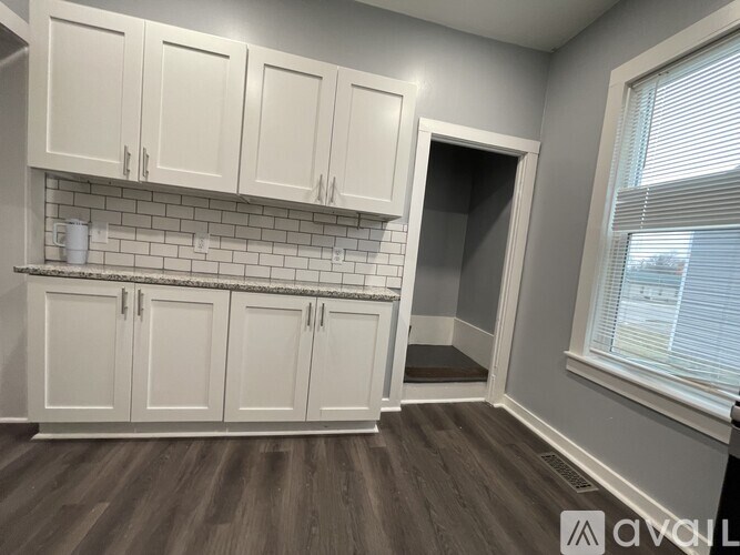 A kitchen with white cabinets and a grey wall.
